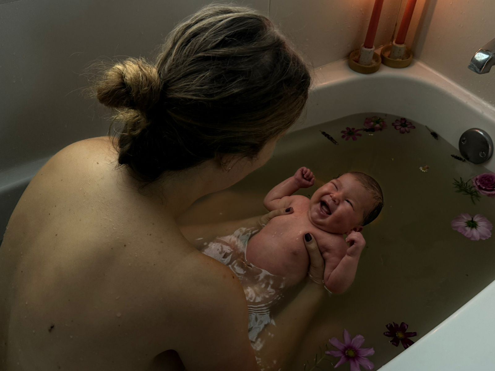 Laughing baby in ceremonial flower bath
